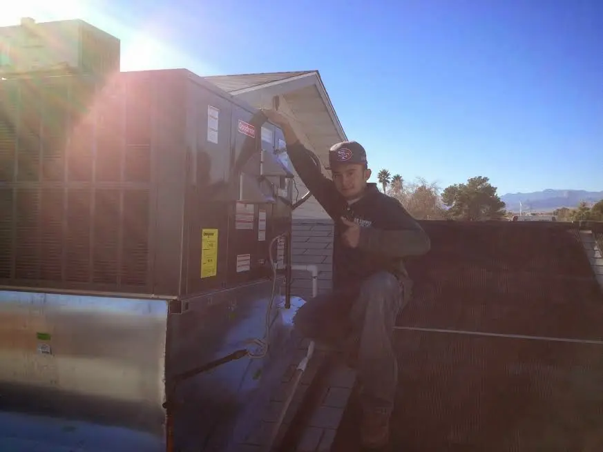 HVAC technician performing AC Tune-Up on a rooftop unit in St. Joseph
